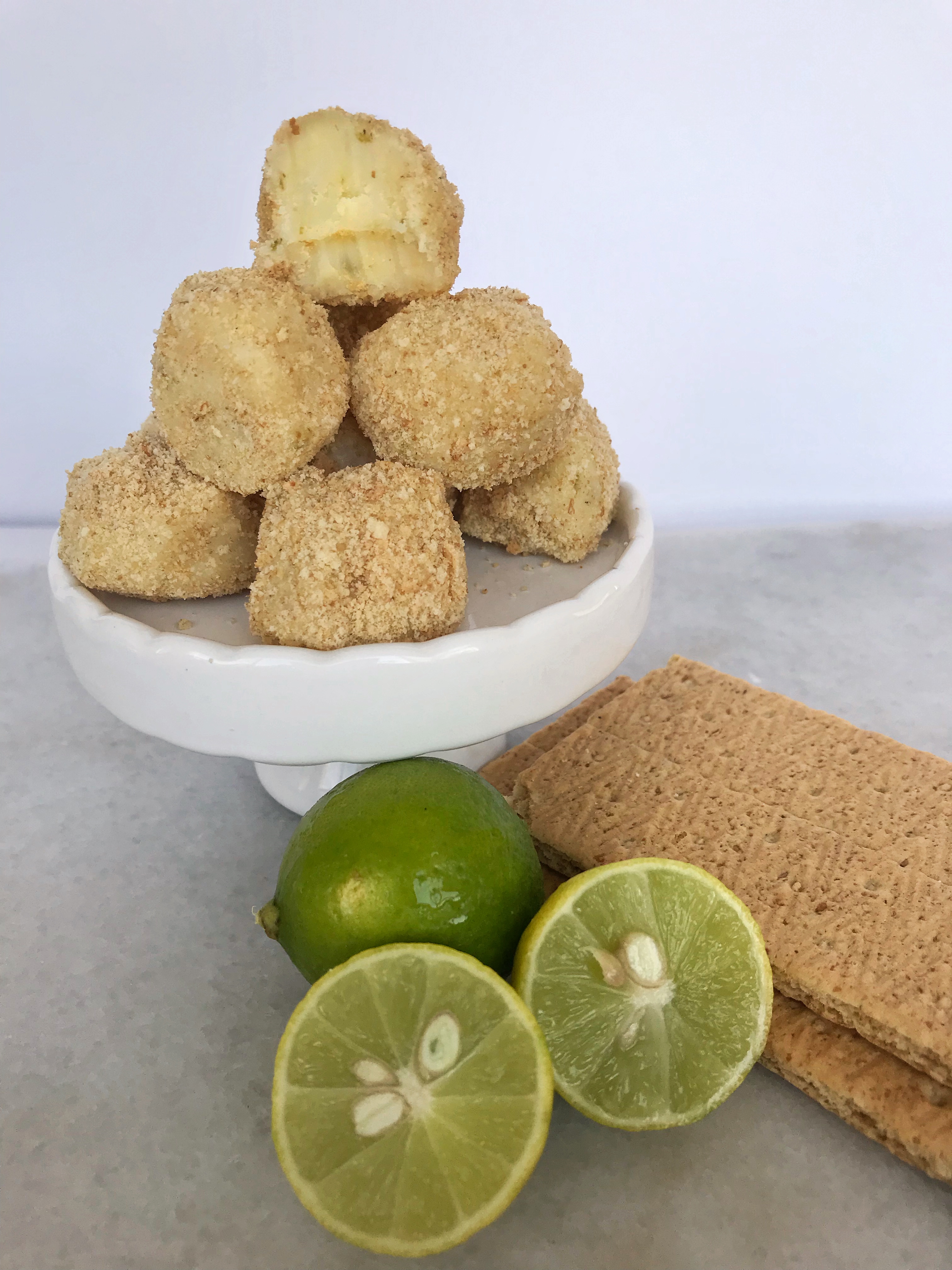 key lime pie truffles on stand with limes and graham crackers