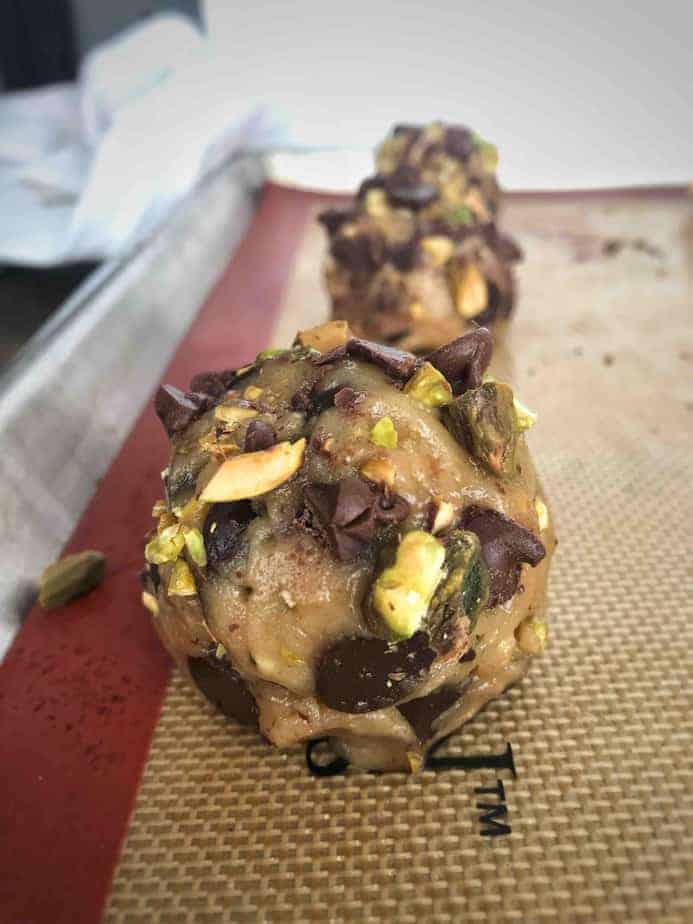 balls of dark chocolate pistachio tahini cookie dough on a baking sheet