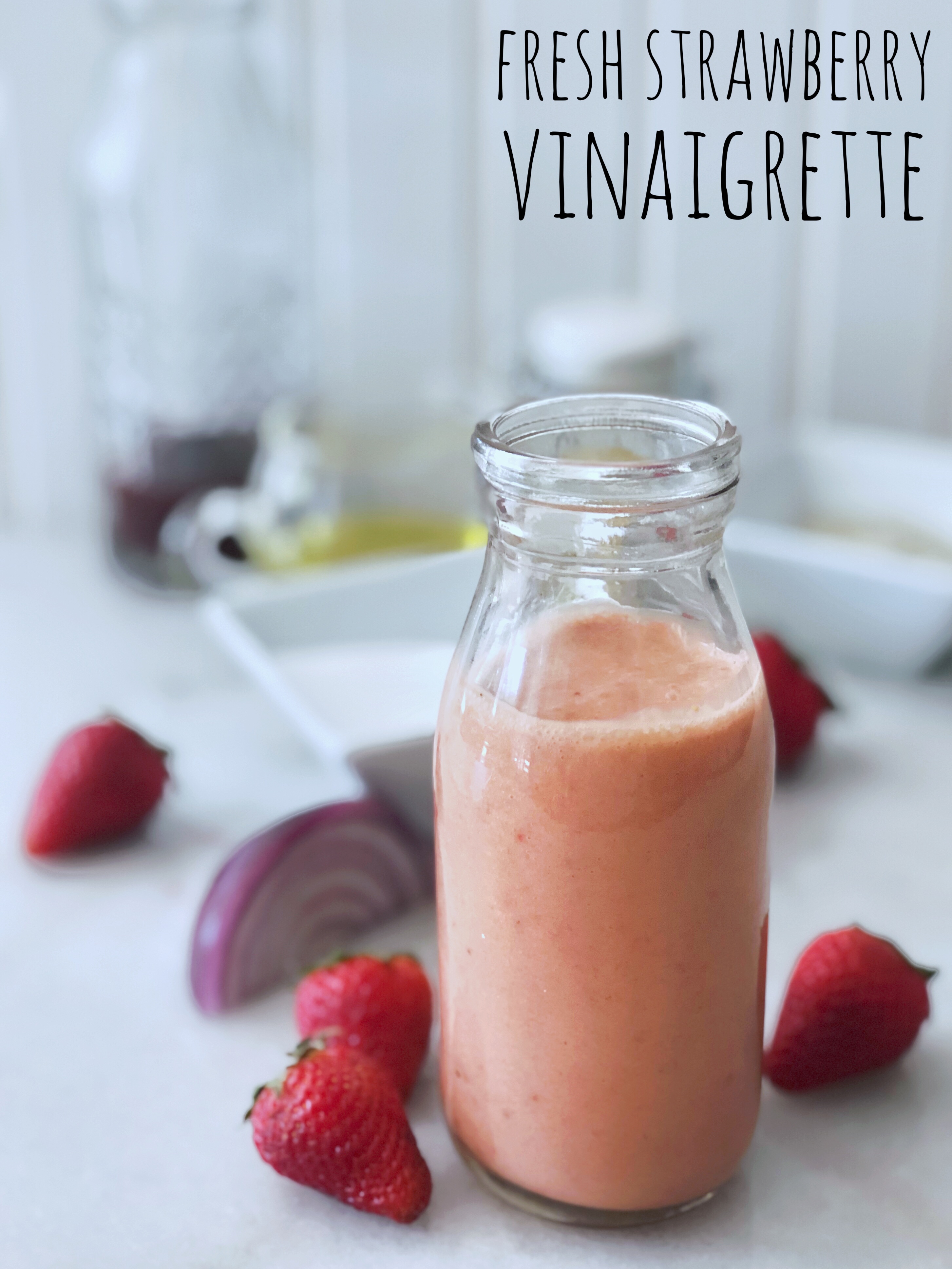 bottle of pink fresh strawberry vinaigrette and scattered ingredients