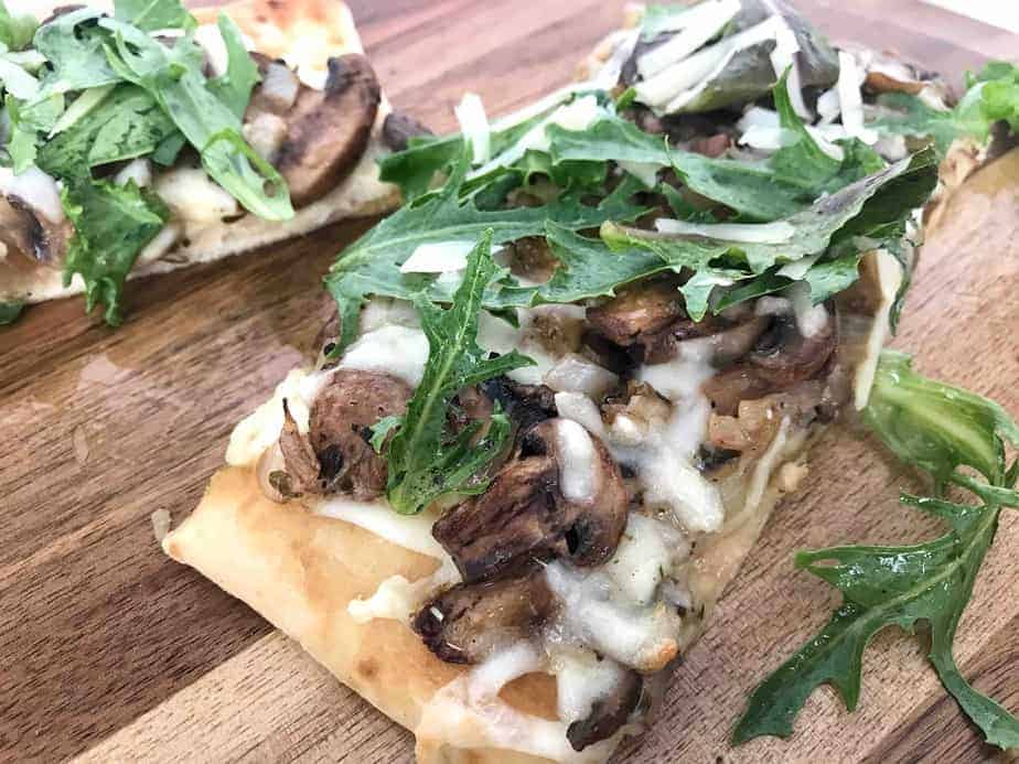 mushroom flatbread pizza with arugula on top