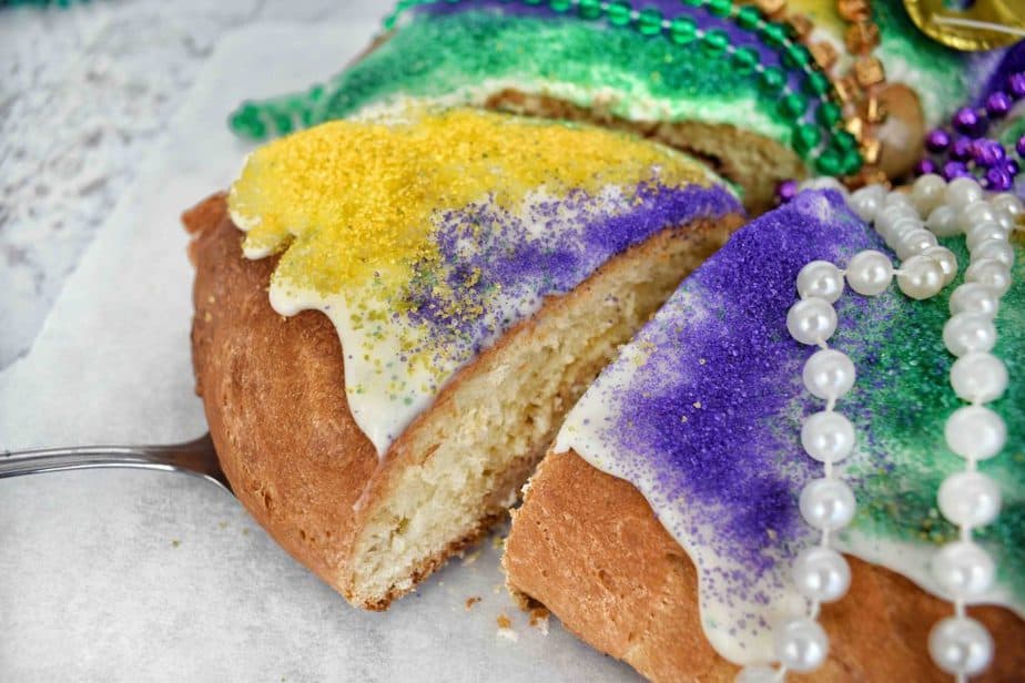 slice being removed from a king cake ring with colored sanding sugar