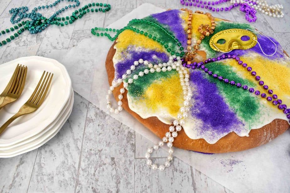 full mardi gras king cake with mardi gras beads and paltes