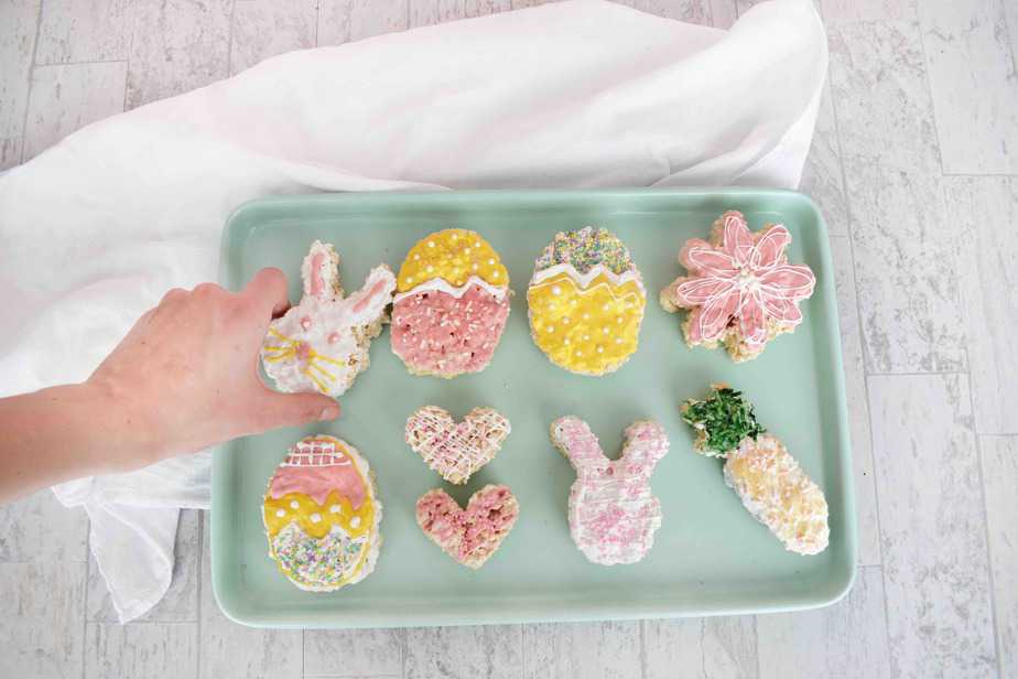 Easter rice krispie treats on blue tray with hand grabbing one