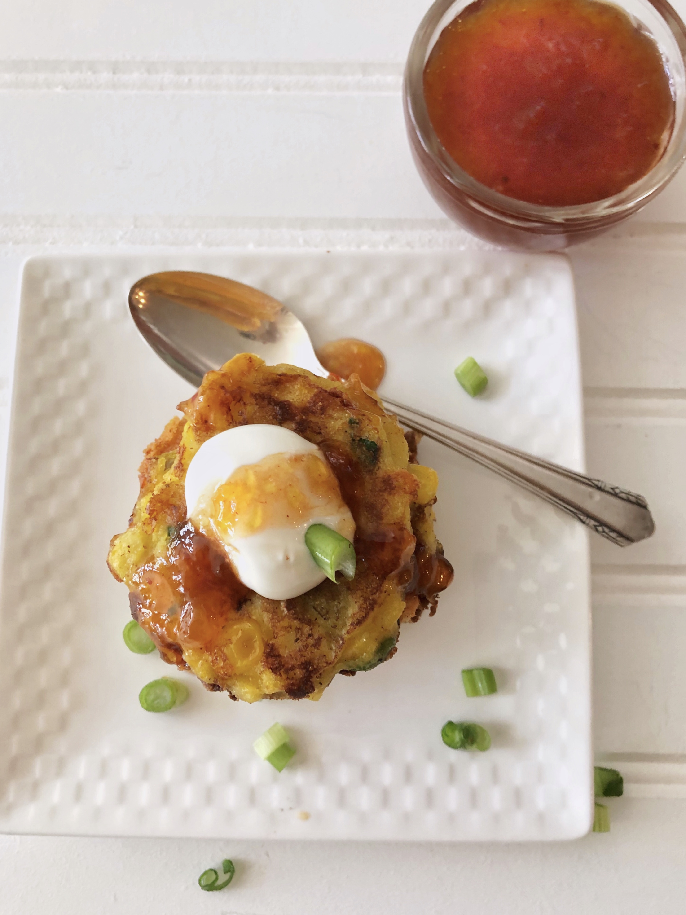 corn fritters with chili peach sauce, sour cream and a spoon
