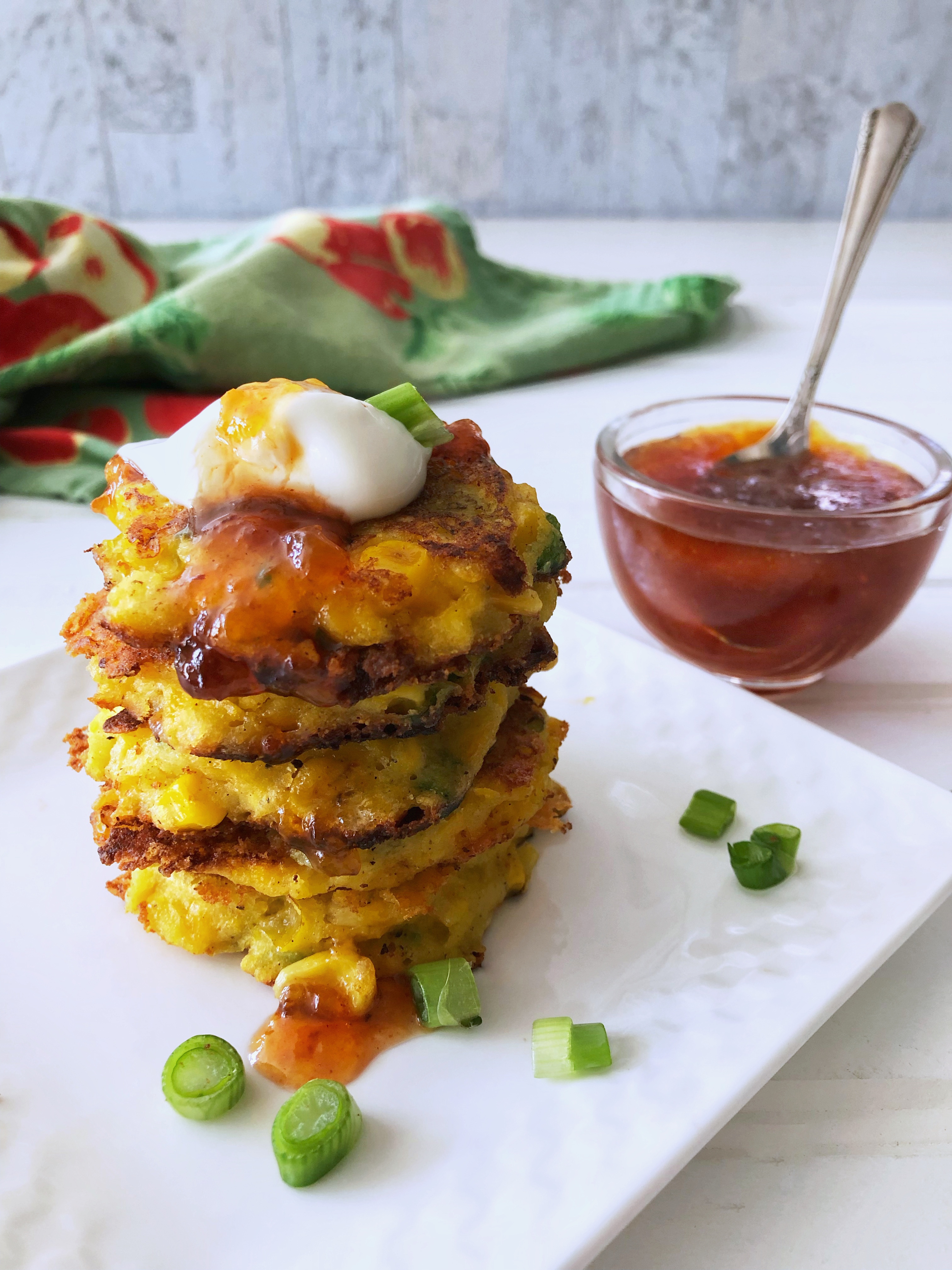 Stack of corn fritters with peach sauce in bowl in back