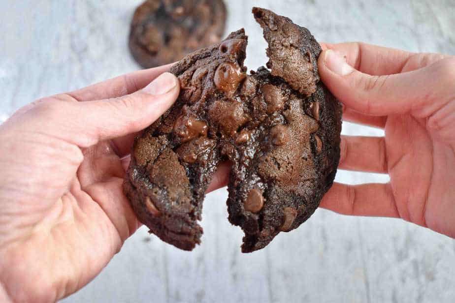 hands breaking double chocolate cookie in half