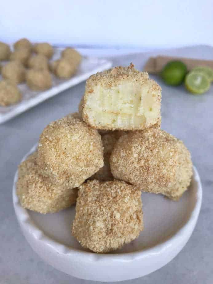 key lime pie truffles on a stand with a bite taken out of it