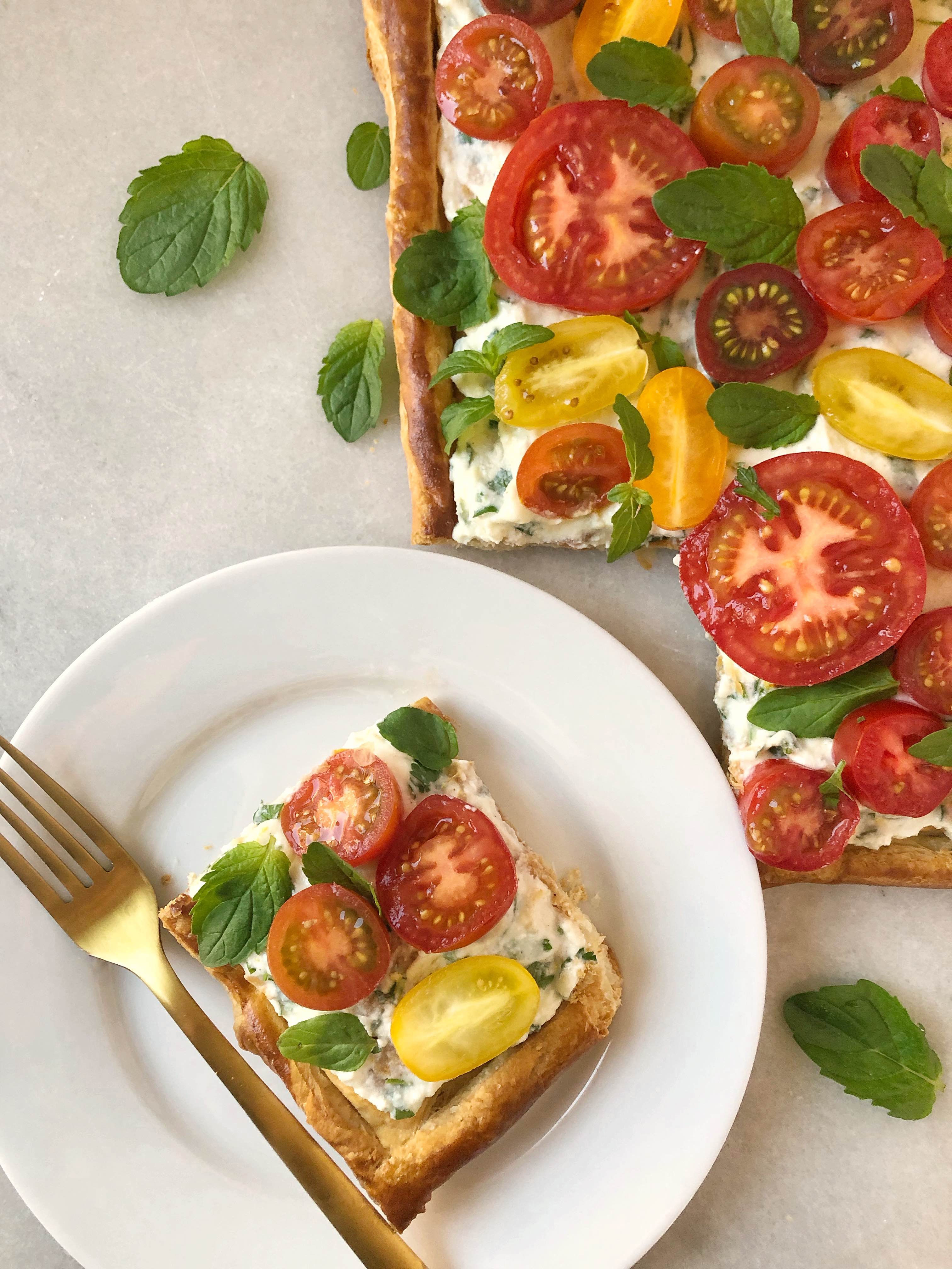 slice of herbed cheese and tomato tart on white plate