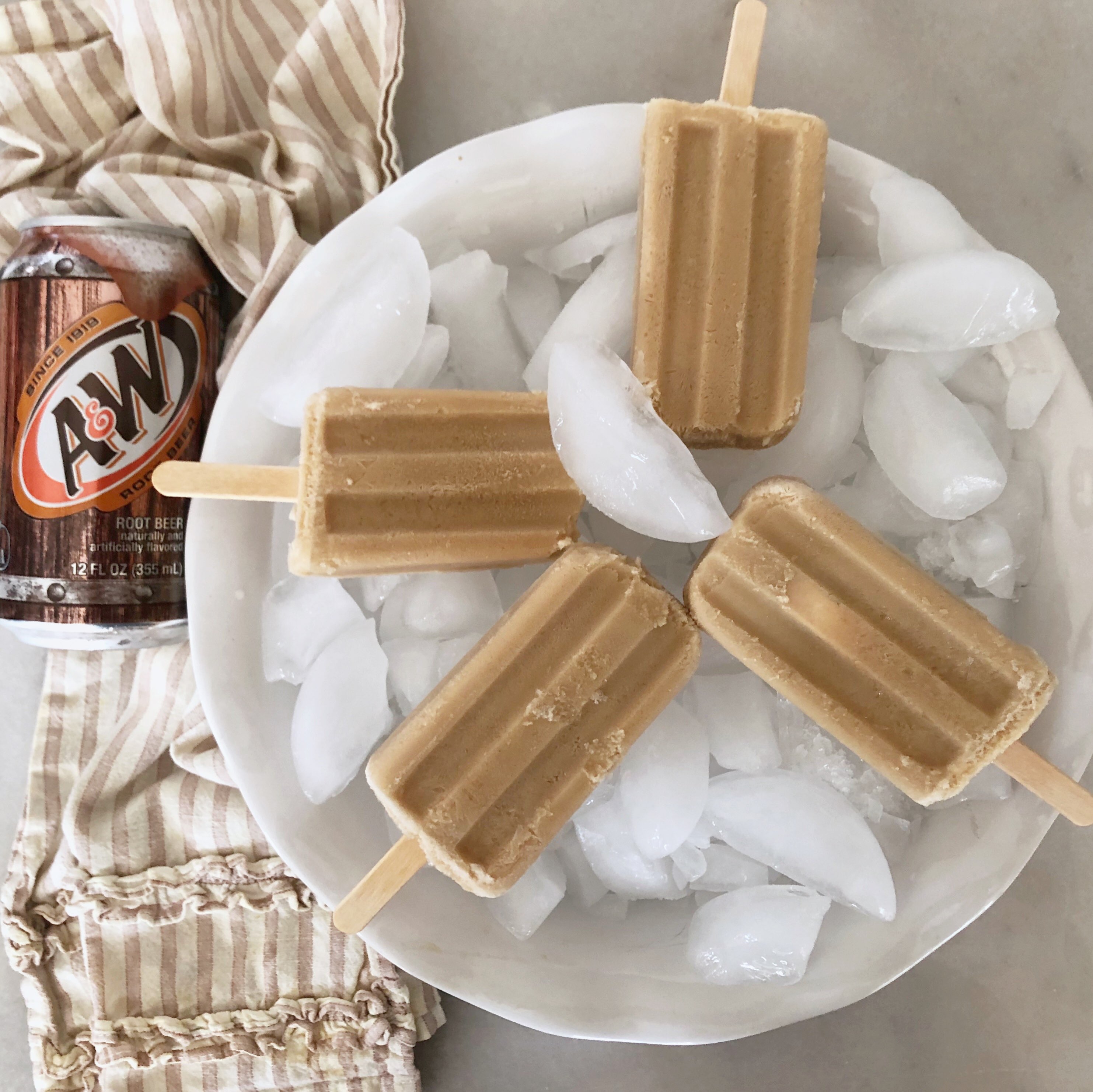 4 rootbeer popsicles on ice with can of A & W rootbeer