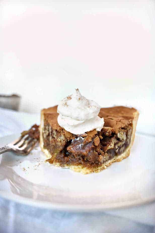 slice of pecan pie with bite out of it with whipped cream on top