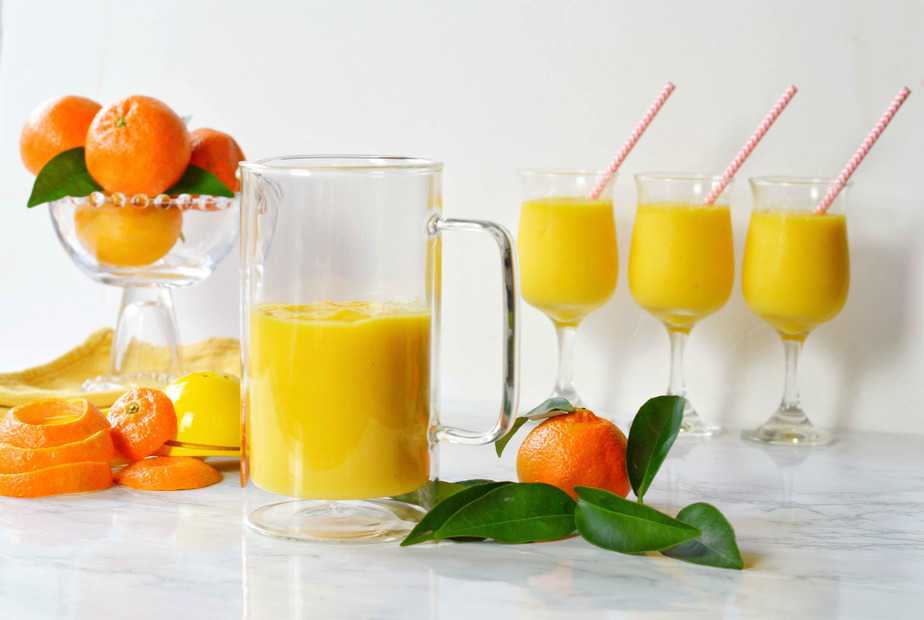 orange mango freeze in glasses and pitcher with tangerines