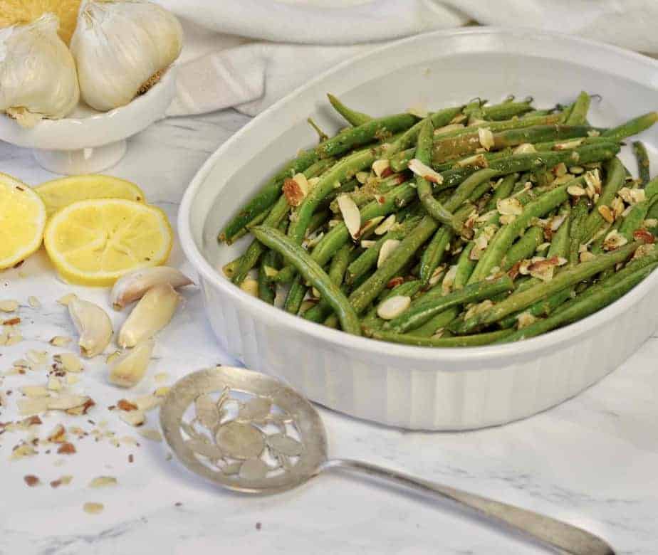 white dish with roasted lemon garlic green beans and almonds
