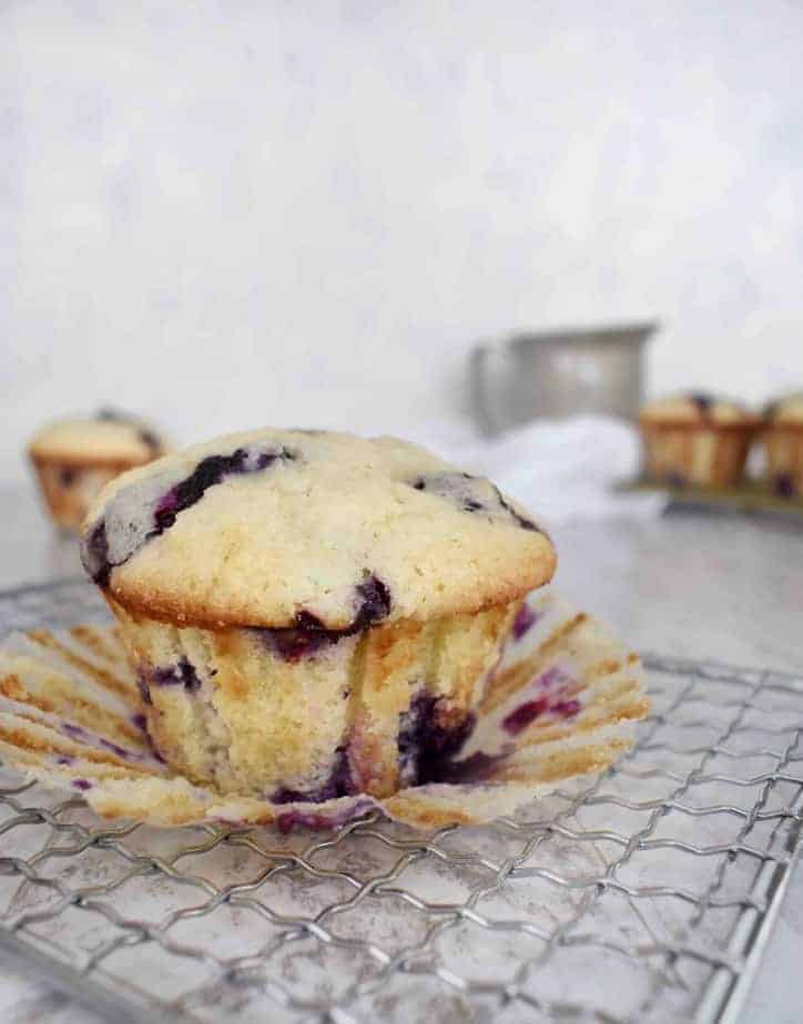 single muffin on cooling rack with paper coming off