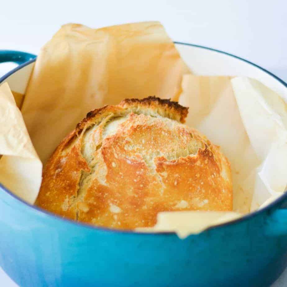 herb artisan bread in blue Dutch oven with parchment paper