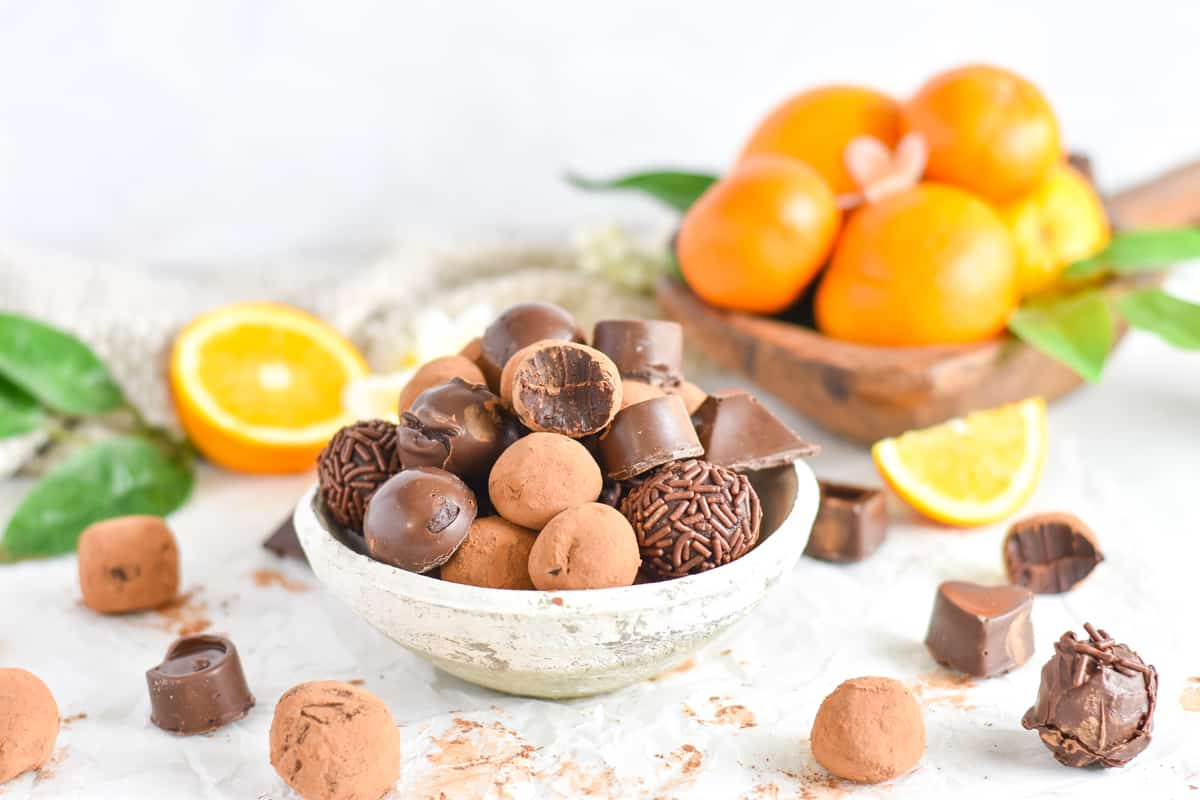 truffles piled in white bowl with oranges in background. 