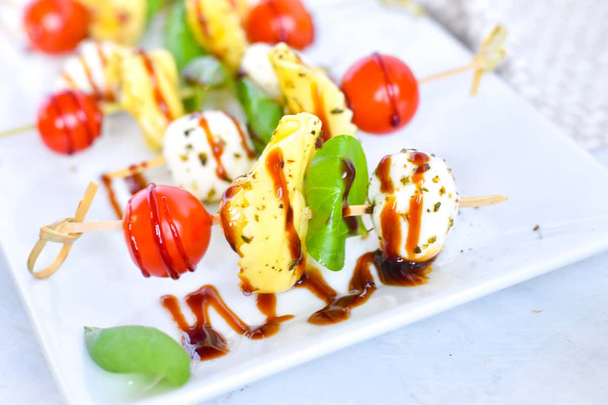 caprese skewers on white platter.
