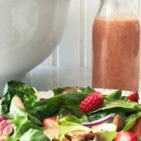 bottle of pink fresh strawberry vinaigrette and plate of strawberry spinach salad