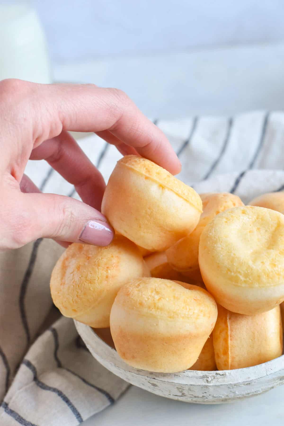 hand grabbing fogo de chao bread out of a bowl.