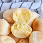 cheese roll torn open top of bowl full of rolls.