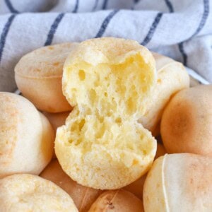 cheese roll torn open top of bowl full of rolls.