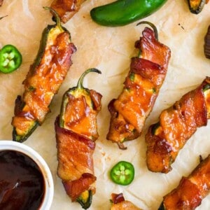 Jalapeno poppers with cup of barbecue sauce next to it.