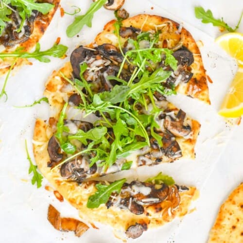 sliced flatbread pizza with arugula on top.