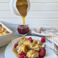 bowl full of bread pudding with raspberry and caramel sauce pouring out