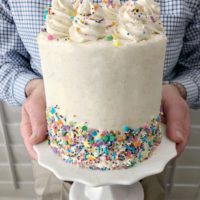 White easy classic vanilla layer cake with sprinkles on a white cake stand