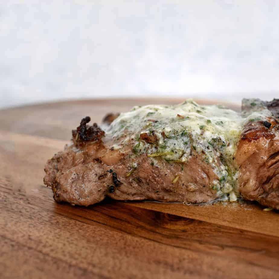 steak on wooden board with bleu cheese butter on top.