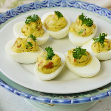Blue and white platter filled with deviled eggs featuring sugared pecans, bacon and jicama.
