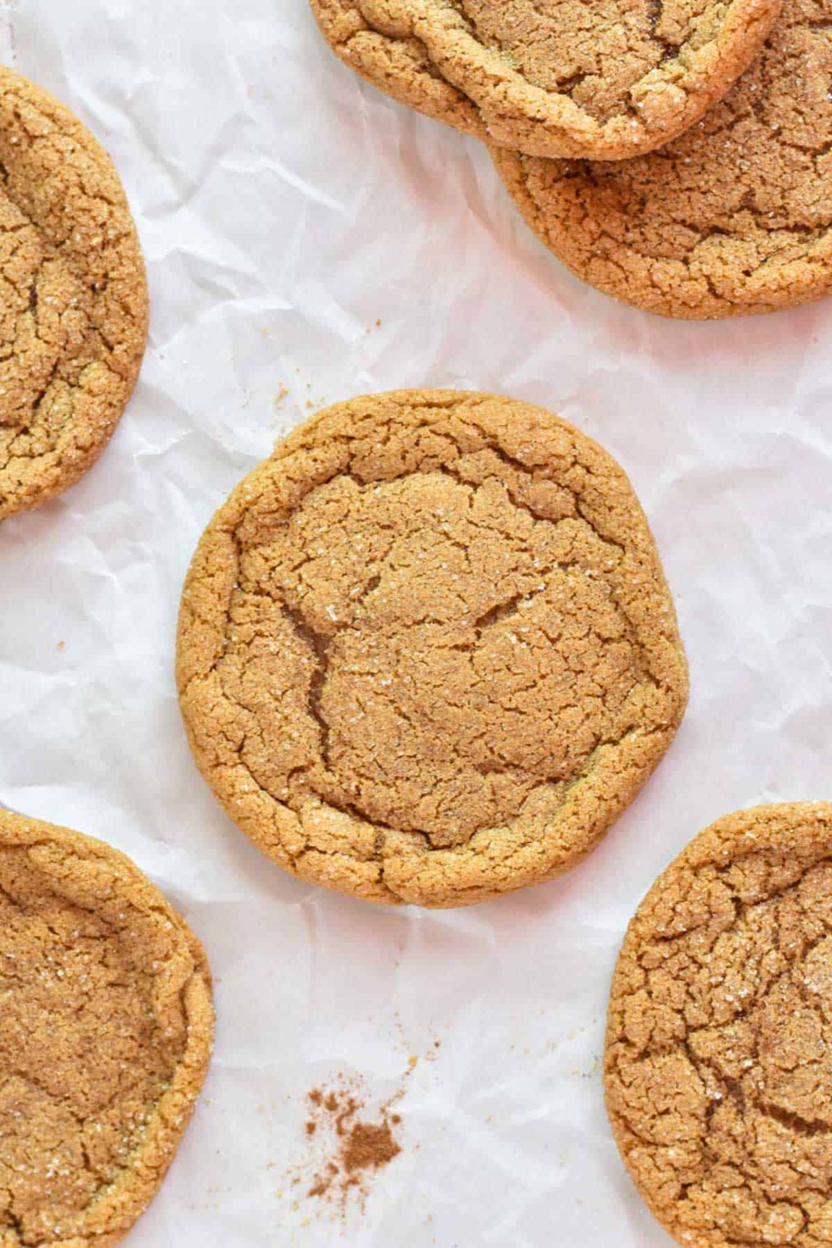 molasses cookie with crinkled top on parchment paper.