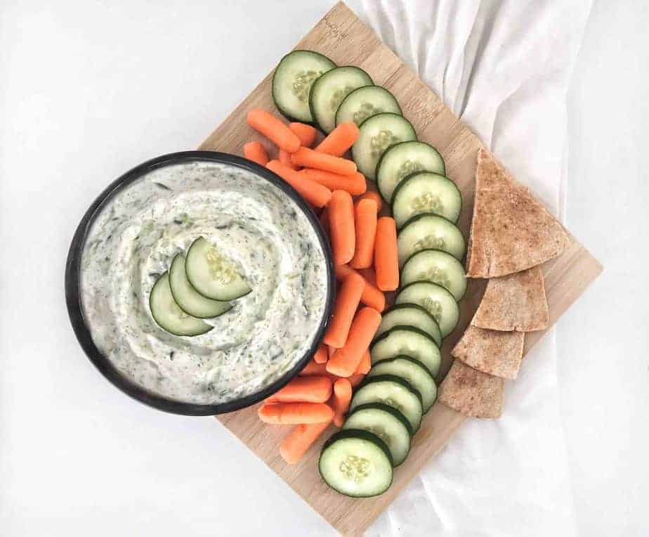 bowl of tzatziki on a platter with vegetables and pita slices