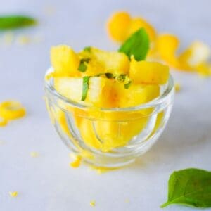 summer salad of pineapple, lemon & basil in glass cup.