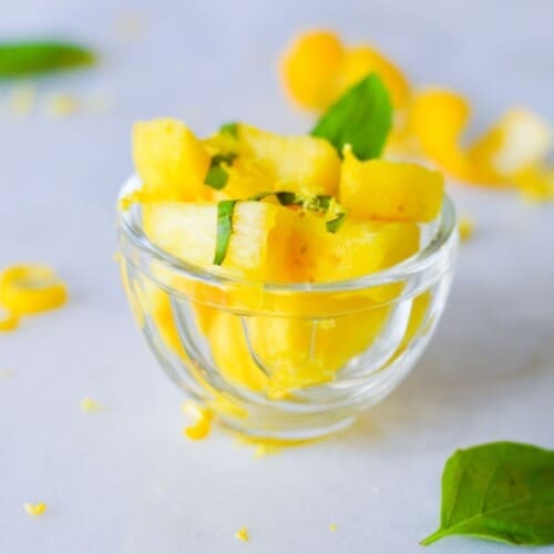 summer salad of pineapple, lemon & basil in glass cup.