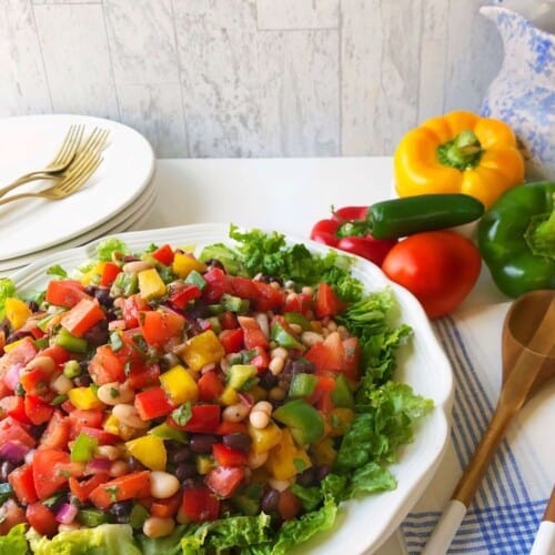 healthy black and white bean salad with colorful vegetables on white platter.