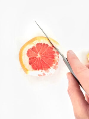 knife removing outer peel of grapefruit.