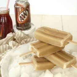 stack of root beer float popsicles on ice with A & W root beer can and glass