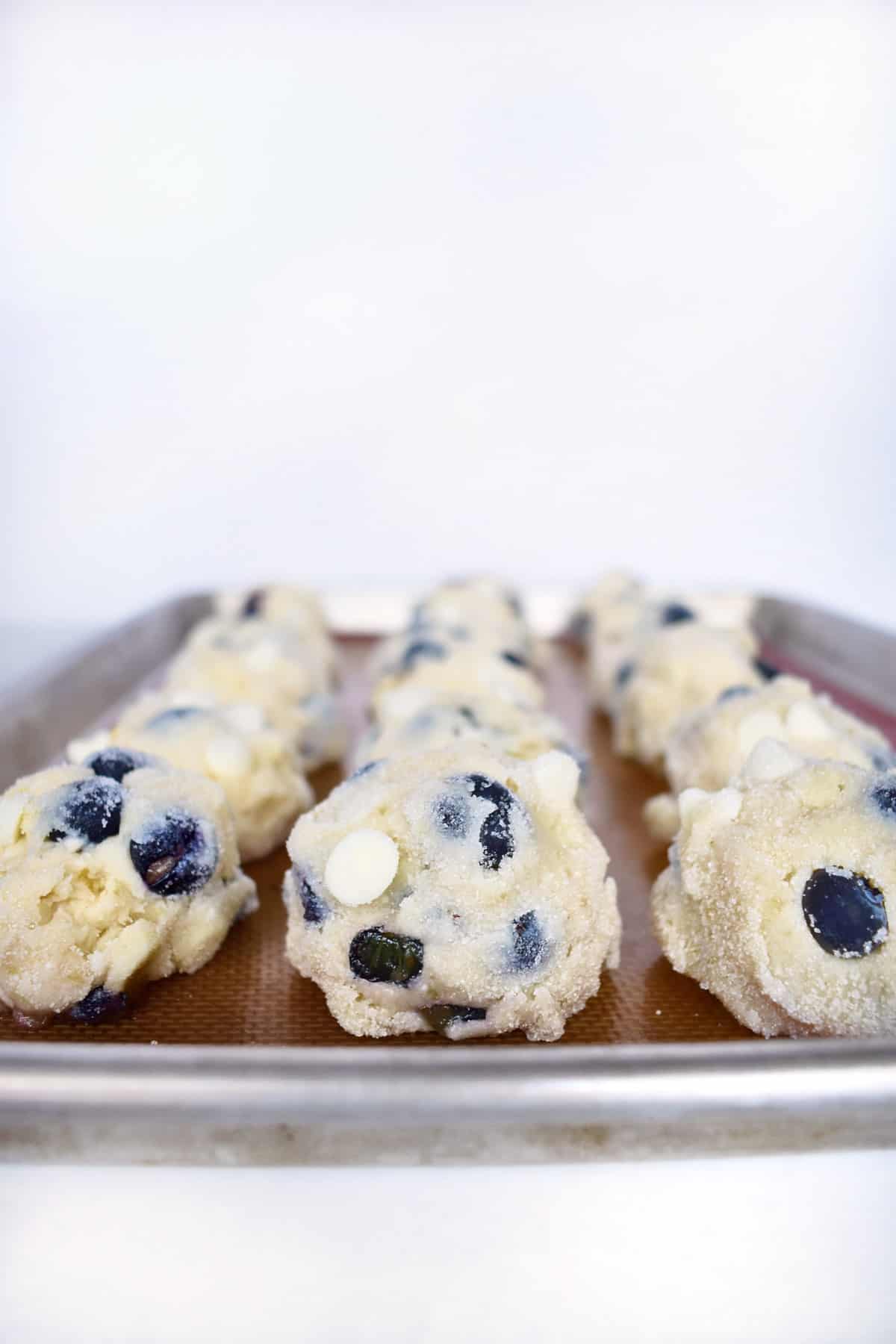 cookie dough balls lined up on cookie sheet