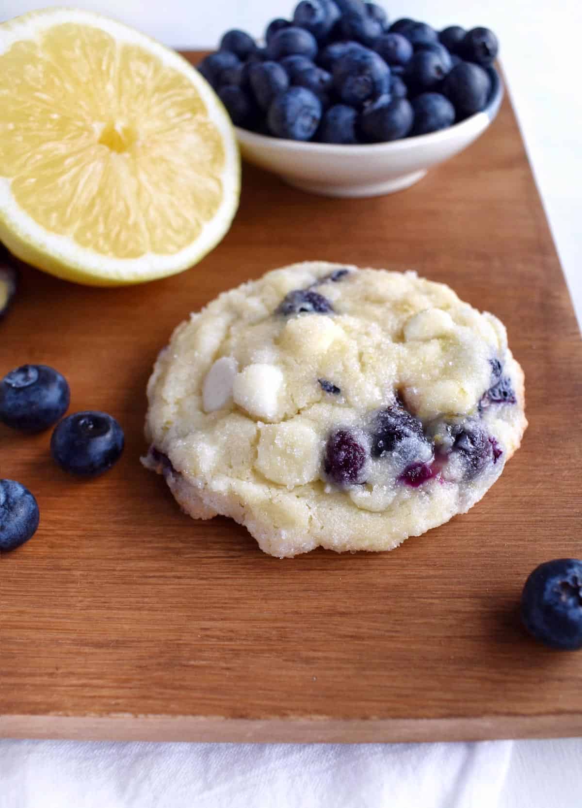 cookie on wooden board with blueberries and lemon in background