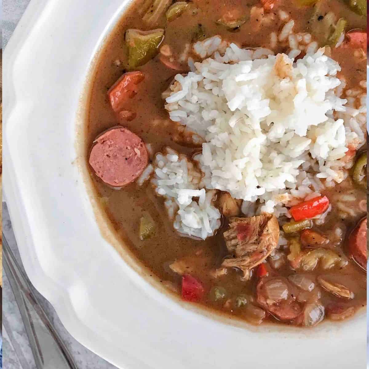 gumbo in a white bowl with rice on top.