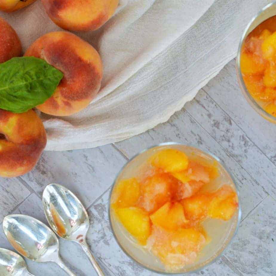 fresh peaches and small glass bowls filled with frozen peaches and other fruits