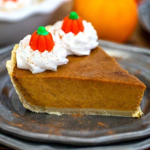 slice of pumpkin pie with whipped cream and little candy pumpkins on top.