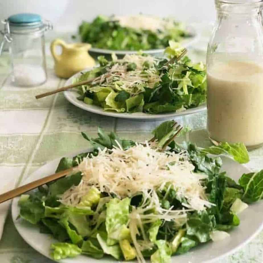 green salad with cheese on top on white plate.
