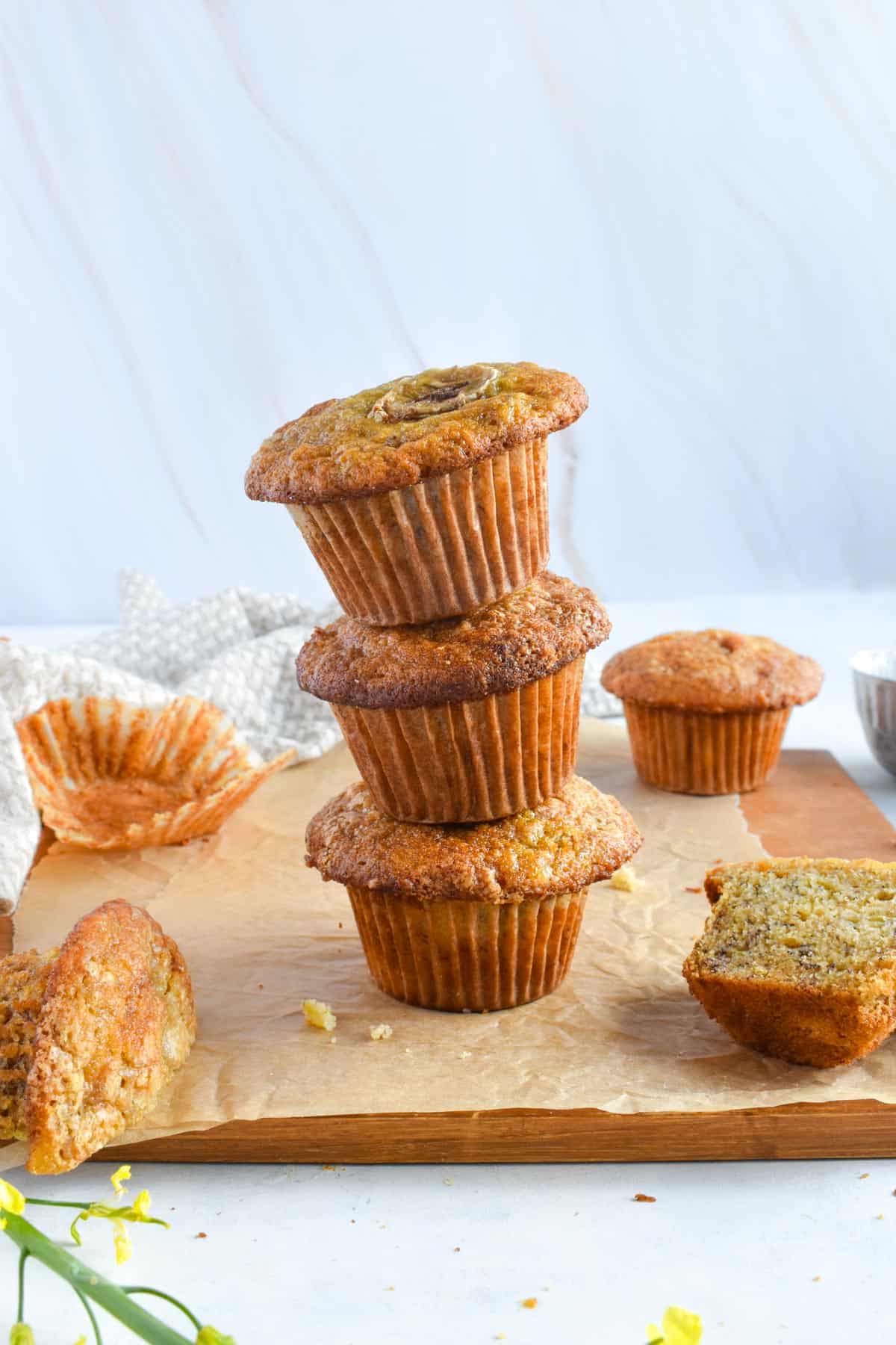 stack of 3 banana muffins on wooden board. 