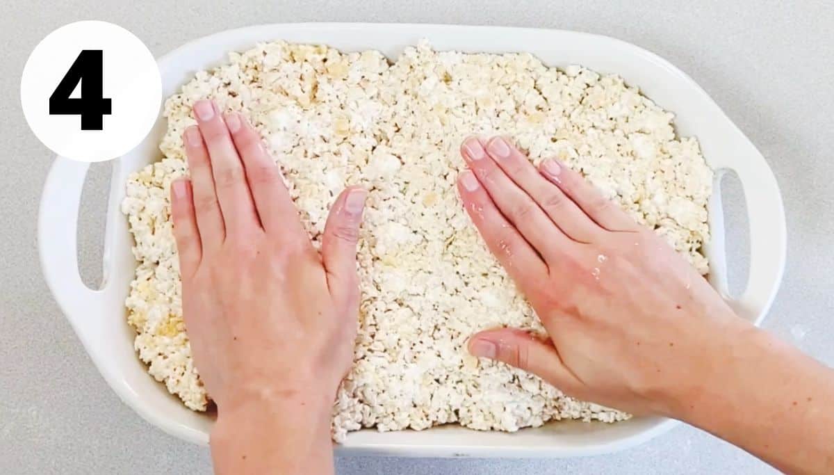hands patting down rice krispie treats in pan. 