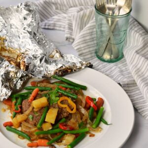 Ground beef patty with vegetables on plate and foil behind