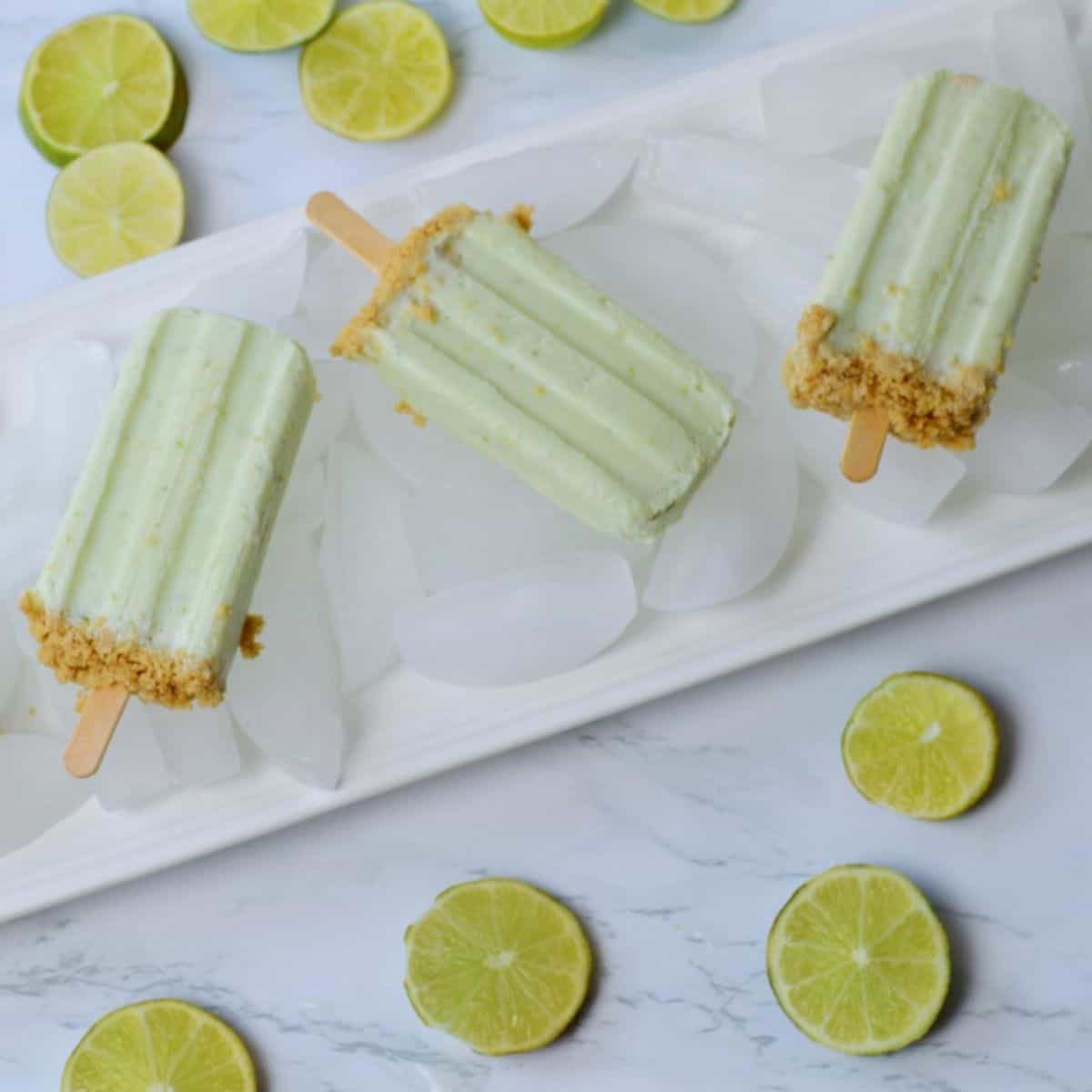 flat white tray with ice and 3 key lime pie popsicles.
