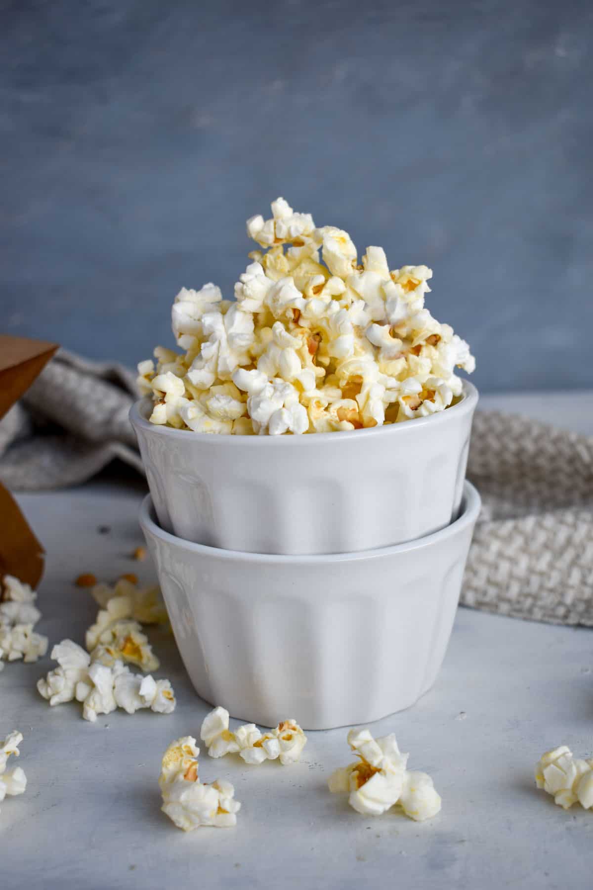 two white cups stacked on top of each other, filled with microwave popcorn. 