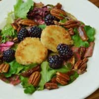 warm goat cheese and spiced pecan salad on white plate