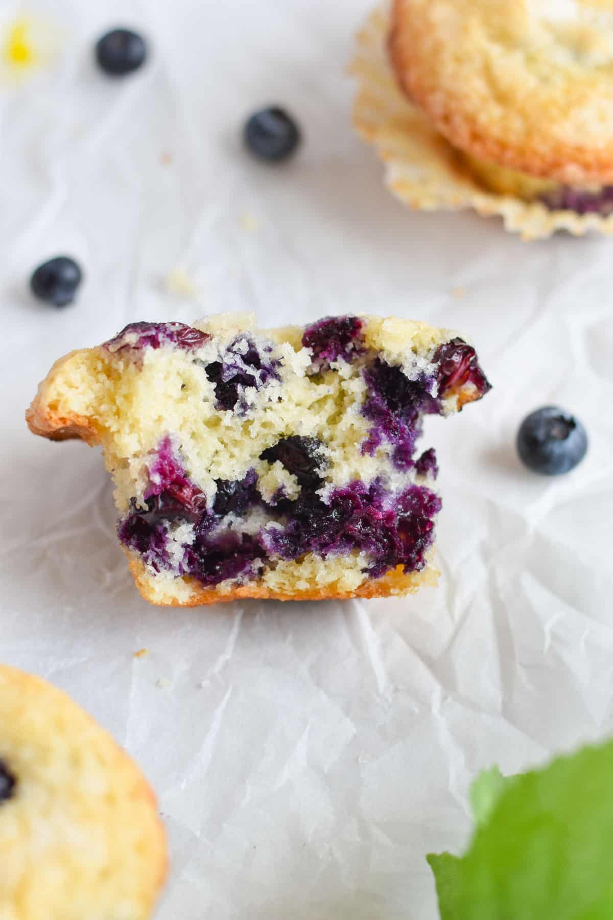 blueberry muffin cut in half with berries around it. 